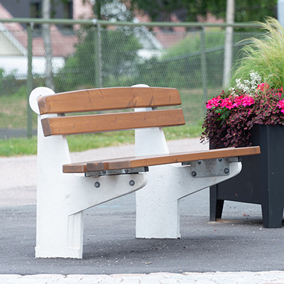 Large park bench with a white concrete frame and wooden seats and backrest.